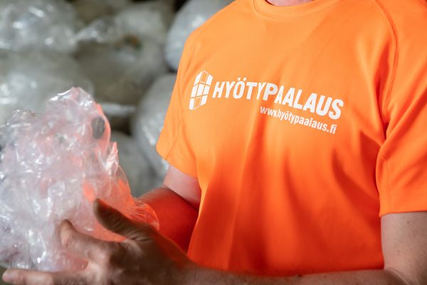 Tampereen Hyötypaalaus Oy.n työntekijä käsittelee kaupalta kerättyä kirkasta muovikäärettä.